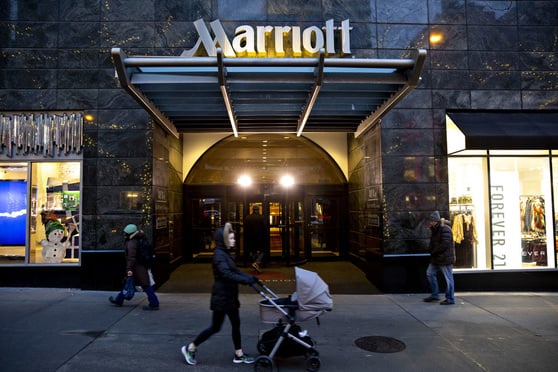 A woman with a stroller walking in front of a Marriott property.