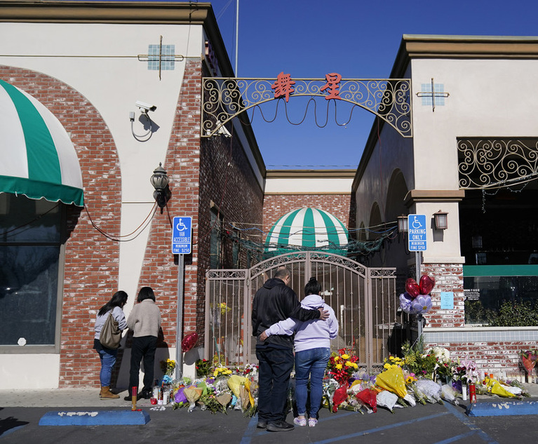 People stand near a memorial outside the Star Ballroom Dance Studio on Tuesday, Jan. 24, 2023, in Monterey Park, Calif. (Credit: Ashley Landis/AP)