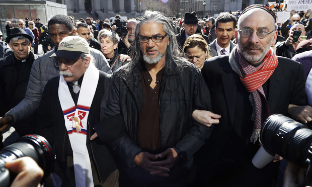 Ravi Ragbir, center, executive director of the New Sanctuary Coalition, a Trinidad-born immigrant who works to protect New York's immigrant families from detention and deportation, walks with supporters as he arrives for his annual check-in with Immigration and Customs Enforcement (ICE) in New York. (AP Photo/Mark Lennihan, File)