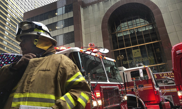 A New York City firefighter responds to the scene where a helicopter crash-landed on the roof of a midtown Manhattan skyscraper, Monday, June 10, 2019, in New York. (AP Photo/Mark Lennihan)