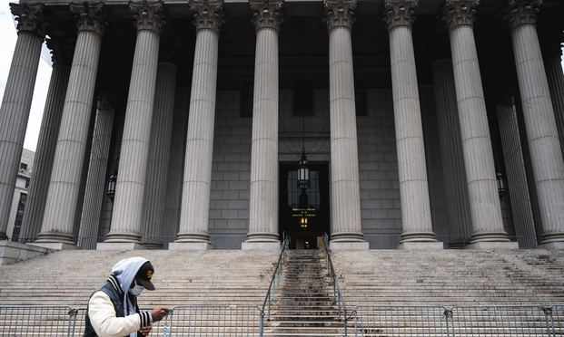 April 9, 2020 A man wearing a mask walks past a New York City Courthouse