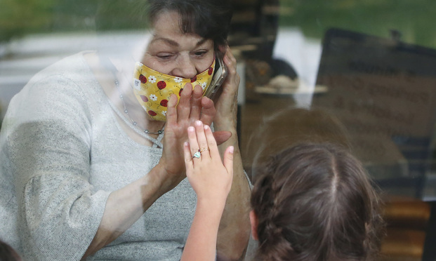 Raelene Critchlow, 86, receives a visit from her great-grandchild Camille Carter, 6, through a window