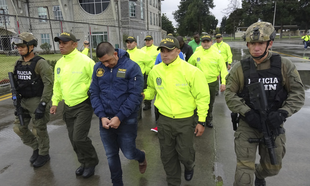 This undated photo released by Colombia's National Police show officers escorting a man who police identify as Ecuadorean drug trafficker Washington Edison Prado after his April 2017 arrest on an indictment by a Florida federal court. (Colombia National Police via AP, File)