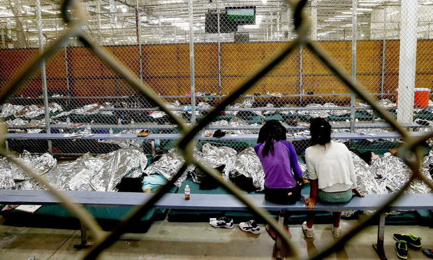 In this June 18, 2014, file photo, two young girls watch a World Cup soccer match on a television from their holding area where hundreds of mostly Central American immigrant children are being processed and held at the U.S. Customs and Border Protection Nogales Placement Center in Nogales, Arizona. The government hasn't worked out a streamlined way to reunite kids and parents who were separated at the border under a new zero-tolerance policy that requires all immigrants who cross the border illegally to be prosecuted. (AP Photo/Ross D. Franklin, Pool, File)
