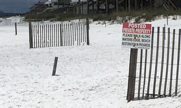A photo shows a sign at the edge of a public beach marking where private beaches begin in Santa Rosa Beach, Florida. (AP Photo/Brendan Farrington)
