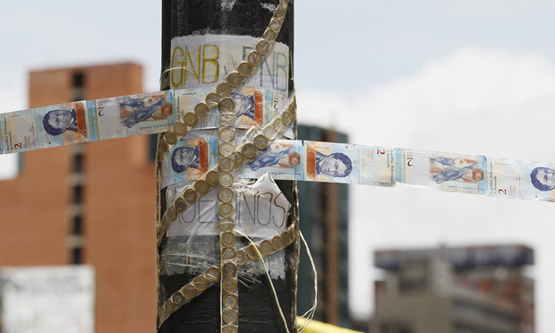 Devalued Bolivar bank notes and coins, taped together, serve as makeshift rope at a roadblock set up by anti-government protesters in Caracas, Venezuela. (AP Photo/Ariana Cubillos, File)