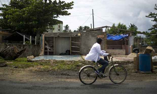 A person rides a bicycle past a home damaged by Hurricane Maria in the town of Punta Santiago, Humacao, Puerto Rico, on Monday, Sept. 17, 2018. Photographer: Xavier Garcia/Bloomberg