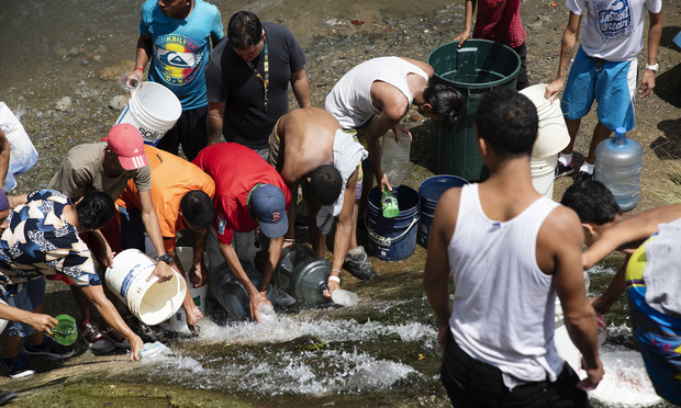 Residents take water from a drainage pipe in the Guaire river in San Agustin, Monagas state, Venezuela, on Monday, March 11, 2019. Caracas began going dry Monday as Venezuela's power crisis put utilities out of commission, risking supplies for 5.5 million people, many of whom found themselves reduced to carrying buckets of filthy river water. Photographer: Carlos Becerra/Bloomberg