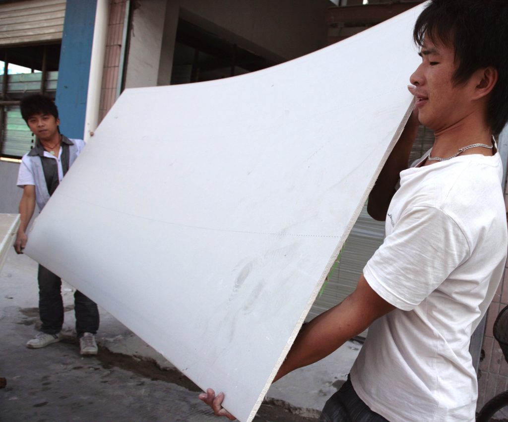 Workers move sheets of drywall at a wholesale market in Shanghai, China, on Monday, Oct. 26, 2009. The U.S., which has halted imports of drywall from China, is testing the products and working with the Chinese government on the investigation. Photographer: Kevin Lee/Bloomberg