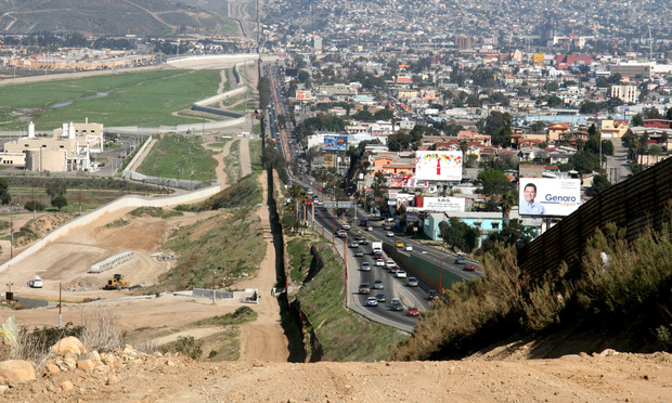A small fence separates densely populated Tijuana, Mexico, right, from the United States in the Border Patrol’s San Diego Sector. Construction is underway to extend a secondary fence over the top of this hill and eventually to the Pacific Ocean. Credit: SFC Gordon Hyde/wikipedia