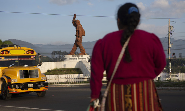 A Quiche indigenous woman stands facing a monument that pays homage to migrants from the town of Salcaja, at the entrance to the town in Guatemala. (AP Photo/Moises Castillo)