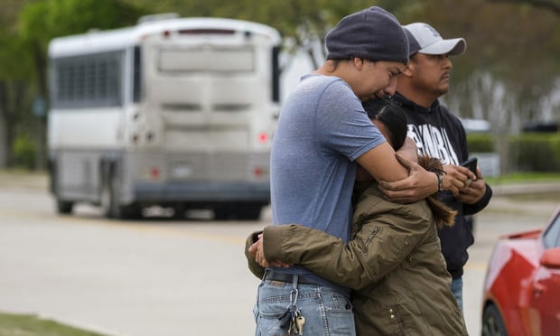 A couple who did not want to give their names embrace outside CVE Group as a bus from LaSalle Corrections Transport departs the facility in Allen, Texas. Smiley N. Pool/The Dallas Morning News via AP, File)