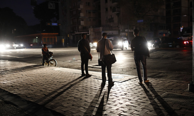 People wait for public transportation on a street during a blackout in Caracas, Venezuela, Monday, July 22, 2019. The lights went out across much of Venezuela Monday, reviving fears of the blackouts that plunged the country into chaos a few months ago as the government once again accused opponents of sabotaging the nation's hydroelectric power system. (AP Photo/Ariana Cubillos)