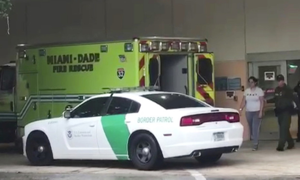 In this image taken from video provided by the Florida Immigrant Coalition, a border patrol agent escorts a woman to a patrol car Sunday, Oct. 13, 2019, at Aventura Hospital in Aventura, Fla. The woman had been detained by border patrol agents when she fell ill. The agent took her to the hospital emergency room for treatment. The presence of immigration authorities is becoming increasingly common at health care facilities around the country, and hospitals are struggling with where to draw the line to protect patients’ rights amid rising immigration enforcement in the Trump administration. (Florida Immigrant Coalition via AP)