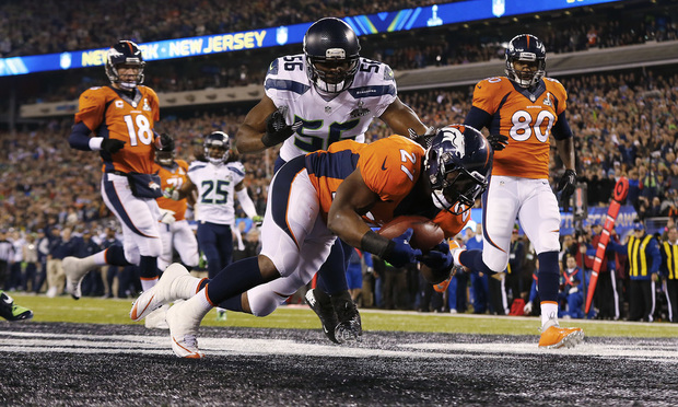 Denver Broncos running back Knowshon Moreno (27) jumps on a fumbled snap as Seattle Seahawks defensive end Cliff Avril (56) prepares to make the tackle for a safety on the first play of the NFL Super Bowl XLVIII football game at MetLife Stadium in 2014, in East Rutherford, New Jersey. The Seahawks won 43-8. (AP Photo/Paul Sancya)