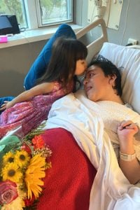 Estefania Mesa receives a kiss from her daughter, Emma, age 4, in a rehabilitation hospital. Mesa cannot speak, move her body or care for herself after suffering cardiac arrest while giving birth to Emma. Courtesy photo