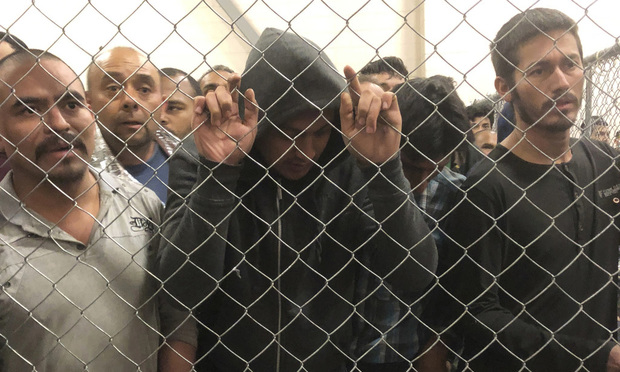 AP Photo: Men stand in a U.S. Immigration and Border Enforcement detention center in McAllen, Texas
