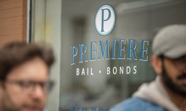 men walk past a storefront for a bail bonds company