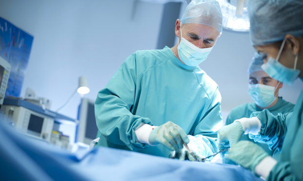 surgeons wearing blue medical gowns in an operating room