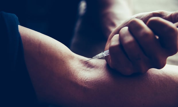 A person injecting a needle into their arm.