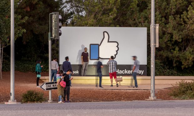 Facebook headquarters sign with people posing for pictures.