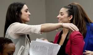 Olympic gold medalists Aly Raisman, right, and Jordyn Wieber embrace during victim impact statements, Friday, Jan. 19, 2018, in Lansing, Mich., during the fourth day of sentencing for former sports doctor Larry Nassar, who pled guilty to multiple counts of sexual assault. (Dale G. Young/Detroit News via AP)