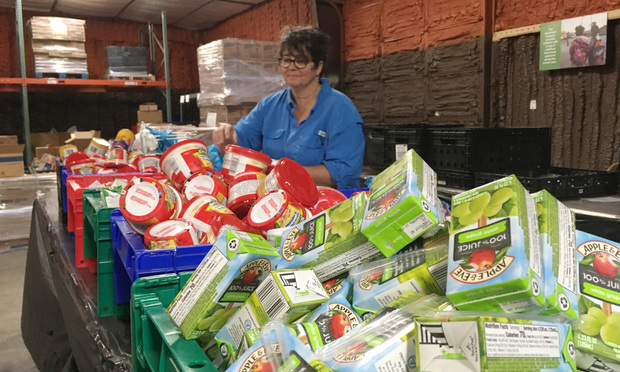 A volunteer in the Faith Food Factory in Augusta pack backpacks for the BackPack Program, which provides elementary school students with four weekend meals each week of the school year.