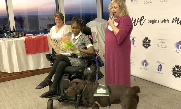 Amber Ross receives flowers from the Georgia Coalition Against Domestic Violence after her service dog, Hershey, checks them out for her. From left, Teresa Millsaps, Amber Ross and Jan Christianen. (Photo: Katheryn Tucker/ ALM)