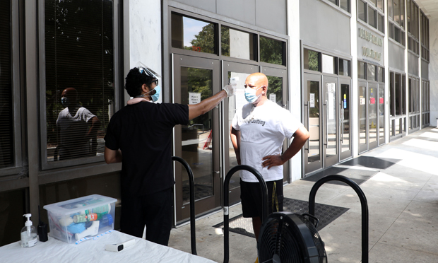 Muhsin Ahmad with Keys Medical checks a visitor's temp before entering the DeKalb County Courthouse in Decatur, Georgia, on Monday, Aug. 31. (Photo: John Disney/ALM)