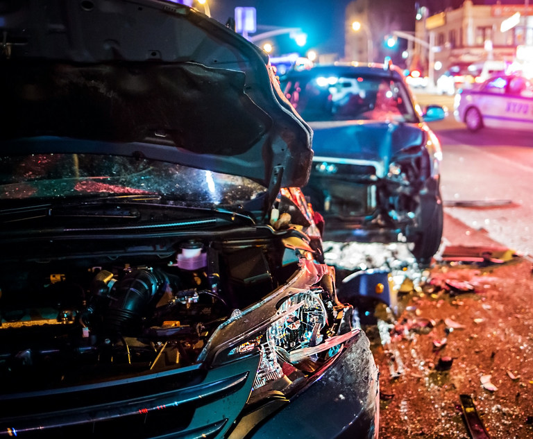 Two vehicles that have collided as a police car sits in the background. Credit: PhotoSpirit/Adobe Stock