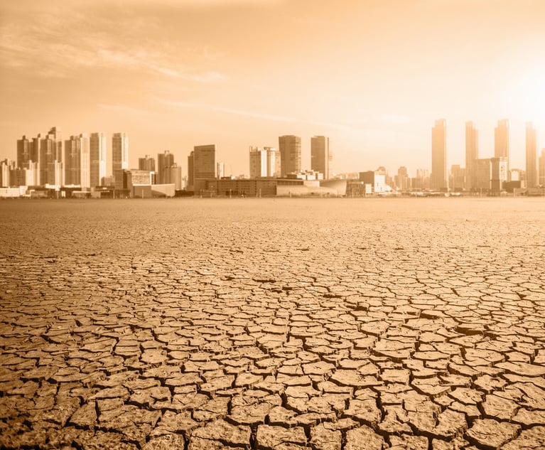 Drought depicted with cracked, dry ground in forefront and city scape in the distance. Credit: scharfsinn86/Adobe Stock