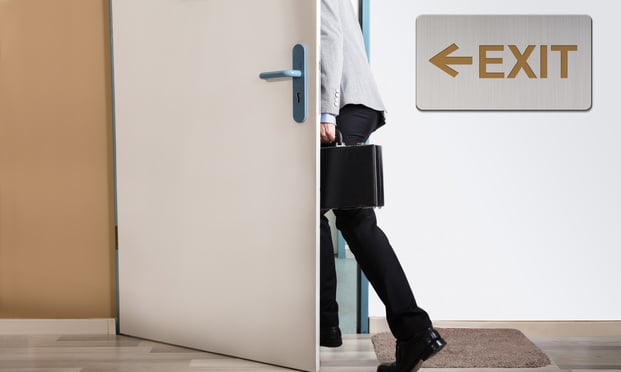 Businessperson Walking Out With Exit Sign On Wall